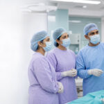 A gynecological surgical team reviewing a laparoscopic monitor in a modern operating theatre.